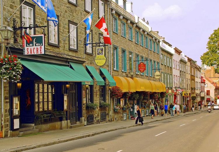 Kanadensisk småföretagare som arbetar med röstinnehållsstrategi med tvåspråkiga marknadsföringsmaterial, Quebec-flagga och professionell ljudutrustning på modernt kontor