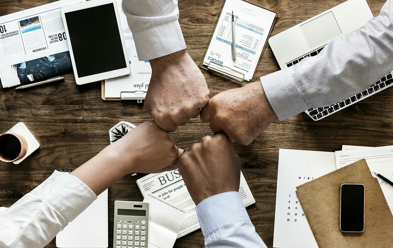 Équipe diverse collaborant sur du contenu éducatif multimédia autour d'une table avec des appareils numériques
