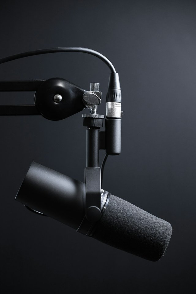 Professional podcast microphone with laptop showing AI text-to-speech software interface and audio waveforms for creating podcasts without recording