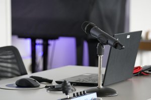 Professional recording studio setup with microphone, headphones, and computer screen displaying Spanish voice content creation software and waveform patterns
