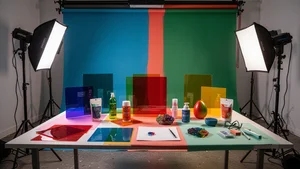 A behind the scenes setup showing color drenched product photography equipment including colored backdrops, gels, and props arranged on a shooting table