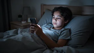 Young person using mental health app in bed late at night with phone glow illuminating face