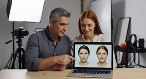 Portrait photographer reviewing images with client on laptop, showing natural retouching results